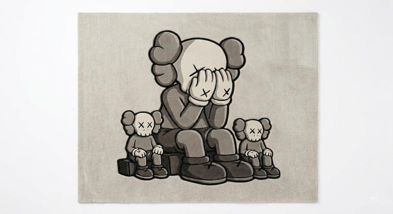 K&ouml;nnte beinhalten: Grau-wei&szlig;er Teppich mit einer Cartoonfigur, die sich die Augen verdeckt, flankiert von zwei kleineren Figuren. Die Figuren haben X-f&ouml;rmige Augen und sitzen. Der Teppich hat einen neutralen Hintergrund.
