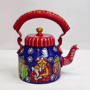 May include: A hand-painted blue teapot with a red handle, lid, and spout. The teapot features a decorative design with figures in traditional clothing and white dot patterns. The handle is arched and the spout is curved.