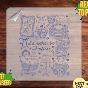May include: A blue DTF transfer featuring a whimsical illustration of various thrifted items. The design includes teacups, plates, a shopping cart, a lamp, and a chicken in a basket. Text reads "I'd rather be thrifting".