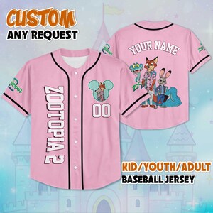 Puede incluir: Camiseta de b&eacute;isbol rosa con ribete negro, con "ZOOTOPIA 2" en la parte delantera y un gr&aacute;fico de dibujos animados. La camiseta incluye el texto "CUSTOM ANY REQUEST" y "KID/YOUTH/ADULT BASEBALL JERSEY". La parte trasera tiene "YOUR NAME" encima de un gr&aacute;fico de dibujos animados.