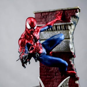 Puede incluir: Una detallada figura de Spider-Man en una pose din&aacute;mica, vestido con su traje rojo y azul caracter&iacute;stico. La figura est&aacute; trepando por una pared de ladrillos, con detalles intrincados en el disfraz y la textura de la pared. La figura mide unos 25 cm de altura.