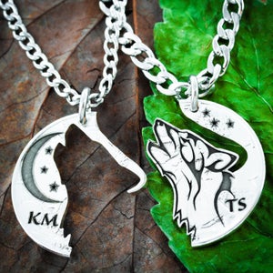 May include: Two silver necklaces with wolf pendants. The pendants are half-circles that fit together to form a complete wolf howling at the moon. One pendant has the initials "KM" and the other has the initials "TS".