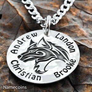 May include: Silver necklace with a round pendant featuring a wolf head design. The pendant is engraved with the names "Andrew Christian Landon Brooke".