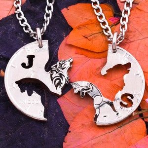 May include: Two silver necklaces with wolf pendants. The pendants are half circles that fit together. One pendant has the letter "J" and the other has the letter "S".