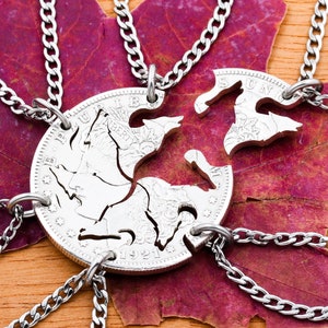 May include: Six silver necklaces with matching pendants, each a piece of a larger coin with a design of a horse. The necklaces are arranged in a circle on a red maple leaf.