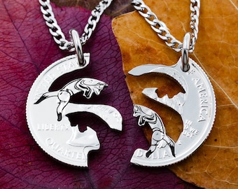 May include: Two silver necklaces with matching pendants, each featuring a half of a silver coin with a bird design. The necklaces are displayed on a brown and purple leaf.