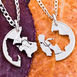 May include: Two silver necklaces with matching pendants shaped like the state of Texas. The pendants are cut in half and fit together to form a complete outline of the state. The necklaces are on a brown and purple background.