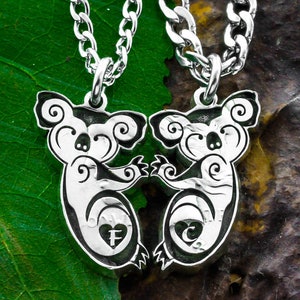 May include: Two silver koala necklaces with a heart and initial charm. The koalas are facing each other and holding hands.