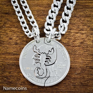 May include: Two silver necklaces with a matching pair of silver quarter dollar coins. The coins are cut in half and feature a scorpion design. The text "UNITED STATES OF AMERICA", "LIBERTY", "IN GOD WE TRUST", and "QUARTER DOLLAR" is visible on the coins.