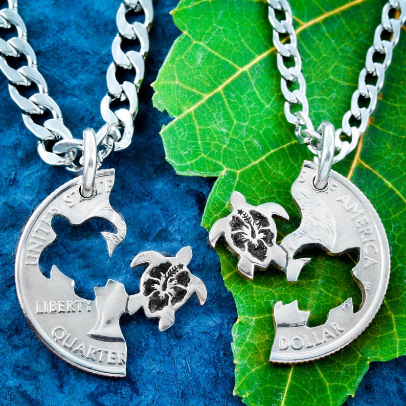 May include: Two silver necklaces with matching turtle pendants. The pendants are made from US quarters and are cut to form two halves of a turtle. Each turtle has a hibiscus flower on its back.