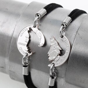 May include: Two black cord bracelets with silver spring clasps. Each bracelet features a silver wolf silhouette cut out of a United States quarter coin.