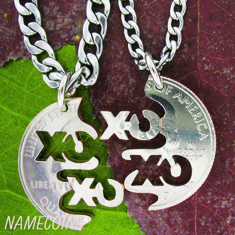 May include: Two silver necklaces with matching pendants. Each pendant is a half-dollar coin with the word "XO" cut out. The coins are joined together to form a heart.