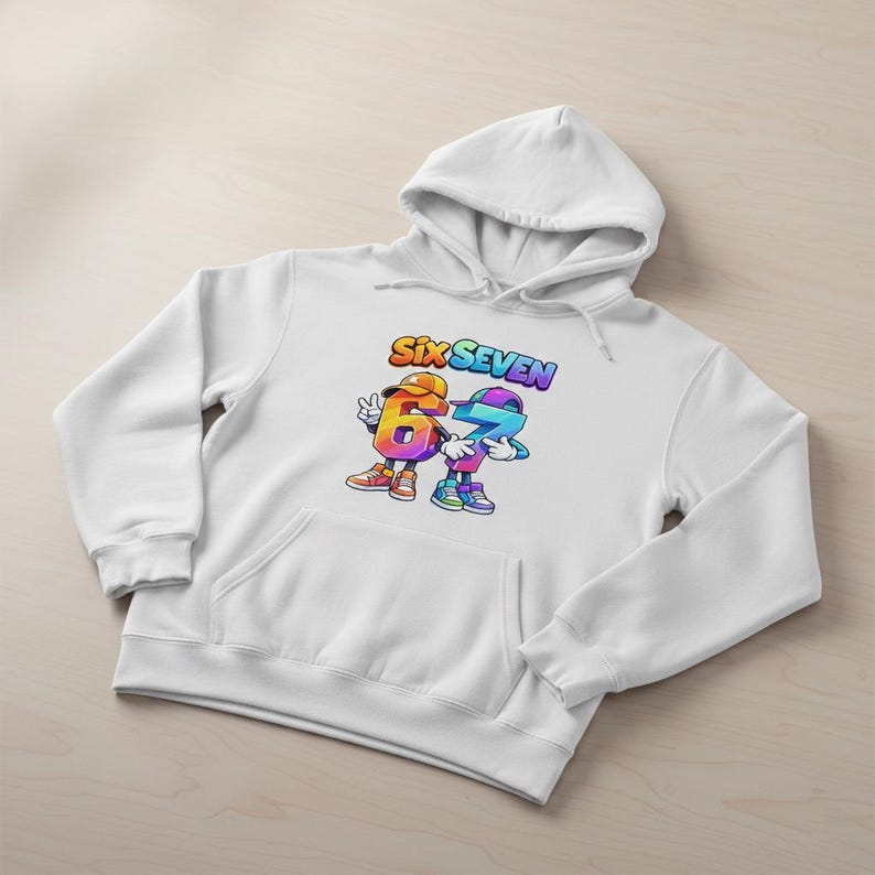 May include: White hoodie with a front pocket and a drawstring hood. The graphic on the front features the words "SIX SEVEN" above two cartoon numbers, six and seven, in vibrant colors. The numbers are wearing hats and shoes.
