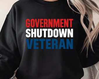 May include: Black sweatshirt with the words "GOVERNMENT SHUTDOWN VETERAN" printed in red, white, and blue. The text is stacked vertically, with each word on a separate line. The sweatshirt is a crew neck style.