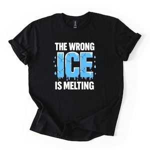 Puede incluir: Camiseta negra con el texto "THE WRONG ICE IS MELTING" en blanco y azul. La palabra "ICE" es de color azul claro con grietas y gotas de agua derritiéndose. La camiseta es de un material suave.