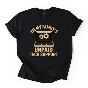 Könnte beinhalten: Schwarzes T-Shirt mit goldfarbener Grafik, die lautet: „I'M MY FAMILY'S UNPAID TECH SUPPORT“. Das Design zeigt einen Laptop mit zwei Zahnradsymbolen auf dem Bildschirm. Das Shirt ist aus weichem Material.