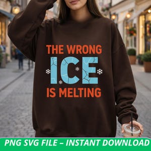 Puede incluir: Una sudadera marrón con el texto "THE WRONG ICE IS MELTING" en naranja y azul. La palabra "ICE" es de color azul claro con un diseño de hielo agrietado y copos de nieve. Es una prenda informal.