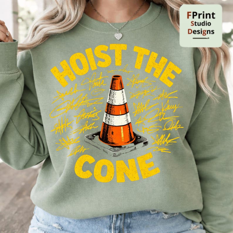 May include: Sage green sweatshirt with the words "HOIST THE CONE" in yellow, along with a graphic of an orange and white traffic cone. The design includes various signatures in yellow around the cone.