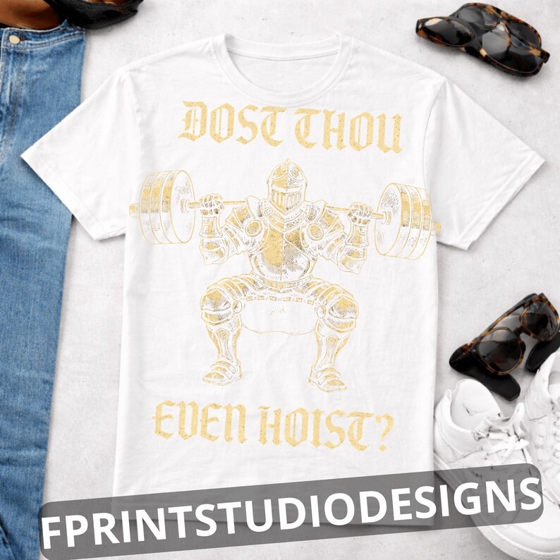 K&ouml;nnte beinhalten: Wei&szlig;es T-Shirt mit einer goldenen Illustration eines Ritters, der Gewichte hebt, mit dem Text "DOST THOU EVEN HOIST?" &uuml;ber und unter dem Bild. Das Shirt hat auch den Text "FPRINTSTUDIODESIGNS" unten.