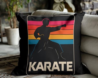 May include: Black square cushion featuring a karate silhouette against a retro sunset design of orange, pink, and blue stripes. The word "KARATE" is printed in white at the bottom.