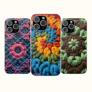 May include: Three smartphone cases featuring textured crochet patterns. The left case has pink and blue floral motifs. The center case displays a vibrant spiral of orange, yellow, green, and blue yarn. The right case shows brown and light green floral designs.