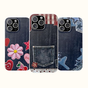 May include: Three smartphone cases featuring a dark blue denim texture. The left case has embroidered patches of a pink flower, red hearts, and cherries. The center case features a denim pocket and red plaid accents. The right case displays blue star patches.