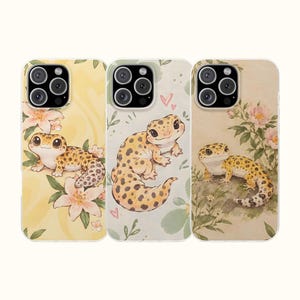 Op de afbeelding: Drie smartphonehoesjes met illustraties van luipaardgekko's. Het linkerhoesje heeft een gele achtergrond met roze bloemen. Het middelste hoesje is lichtgroen met kleine hartjes en blaadjes. Het rechterhoesje toont een gekko tussen roze bloemen.