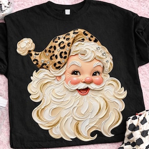 May include: A black t-shirt featuring a graphic of a Santa Claus face with a thick, textured white beard and mustache. Santa wears a tan hat with a black leopard print pattern and small clear rhinestones embedded along the hat's edge.