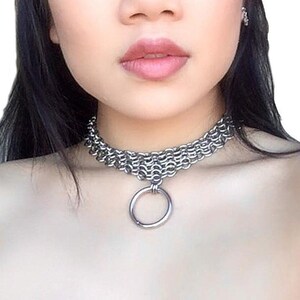 May include: A silver chain choker necklace with a large silver ring pendant.