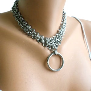 May include: A silver chain choker necklace with a large silver ring pendant.