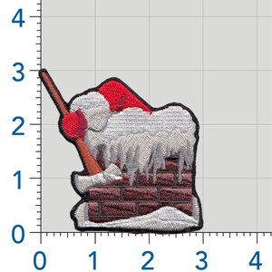 May include: An embroidered patch featuring a red Santa hat resting on a brown brick chimney covered in white snow and icicles, with a brown-handled axe embedded in the top. The patch is positioned against a grid showing a height of 3 inches.