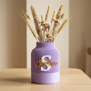 May include: A white ceramic mug with a black handle and the text "But First, Coffee" in a bold, black font. The mug is set against a blurred background, suggesting a cozy setting.