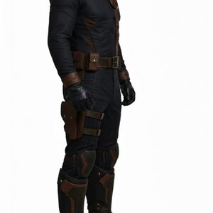 Pu&ograve; includere: Costume nero e marrone con collo alto, tracolla e cintura multiuso. L'outfit include guanti, ginocchiere e stivali. Un'emblema rosso e bianco &egrave; visibile sul petto. Il costume &egrave; per cosplay o eventi a tema.