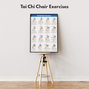 May include: A framed poster titled "Tai Chi Chair Exercises" displays illustrated instructions for various seated exercises. The poster is mounted on a wooden and metal adjustable stool. The background is a plain white wall.