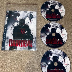 May include: A DVD set of "Daredevil: Born Again - Complete Season Two" featuring Charlie Cox, Vincent D'Onofrio, Krysten Ritter, and Jon Bernthal. The set includes the DVD case and three discs, each with the show's title and cast.