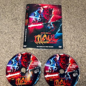 Op de afbeelding: DVD-box van Star Wars: Maul: Shadow Lord, The Complete First Season. De cover toont Darth Maul met een rood-zwart kleurenschema. Twee schijven zijn gemarkeerd met "Schijf 1" en "Schijf 2".
