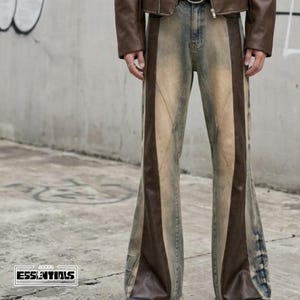 May include: Faded denim jeans with brown leather-like panels down the sides. The jeans have a flared leg design and a distressed look. The image also shows a brown leather jacket and the text "ESSENTIALS".