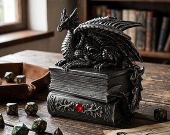 May include: A detailed, silver-colored dragon figurine perched atop a stack of faux books. The books have ornate designs and a red gem. Dice and a character sheet are scattered on the wooden surface, suggesting a tabletop game theme.
