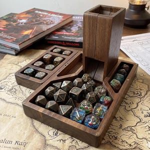 May include: A wooden dice tower and tray set with various dice. The set includes a tower, two trays, and multiple dice in different colors and designs. The trays are filled with polyhedral dice, and the set is on a map.