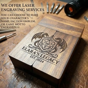 May include: A rectangular dark wood box featuring a laser-engraved design of a twenty-sided die flanked by two dragons. The text reads: WE OFFER LASER ENGRAVING SERVICES. YOU CAN CHOOSE TO HAVE YOUR CHARACTER'S NAME, FACTION EMBLEM, OR GAME MOTTO ENGRAVED. ELARA'S LEGACY EST. 2024.