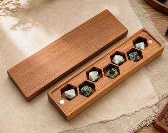 May include: A rectangular wooden box with a removable lid, featuring six hexagonal cutouts designed to hold polyhedral dice. The box is crafted from medium-toned wood and contains five multi-colored dice with gold numbering inside the slots.