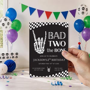 May include: A rectangular birthday invitation card with a black background and white checkered borders. It features a white skeleton hand making a rock-and-roll gesture, with the text BAD TWO the BONE, JACKSON'S 2ND BIRTHDAY, and event details.