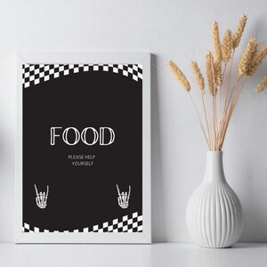 May include: A framed black and white sign with the word "FOOD" in a bold, stylized font. The sign also includes the text "PLEASE HELP YOURSELF" and two skeleton hand illustrations. A checkered pattern borders the top and bottom of the sign.