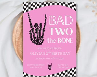 May include: A pink birthday invitation with a black and white checkered border. The invitation features the text "BAD TWO the BONE" and a skeleton hand gesture. The invitation is for Olivia's 2nd birthday, with the date and time included.