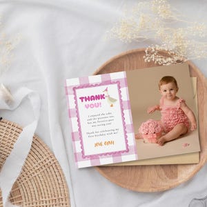 May include: A birthday thank you card featuring a baby in a pink outfit and a floral arrangement. The card has a pink gingham border and the text "THANK YOU!" with a message and "LOVE OLMA."