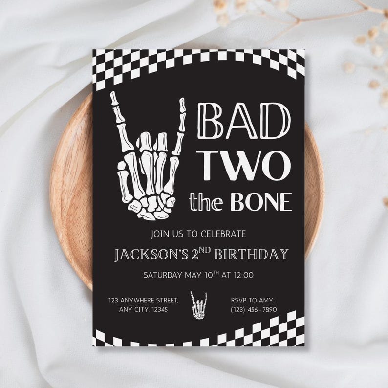 May include: A rectangular birthday invitation card with a black background and white checkered borders. It features a white skeleton hand making a rock-and-roll gesture, with the text BAD TWO the BONE, JACKSON'S 2ND BIRTHDAY, and event details.