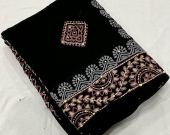 May include: A folded black fabric featuring a decorative border with grey and mauve floral patterns, accented by small gold sequins. A central square motif in mauve and grey sits on the black field, with additional gold sequin detailing.