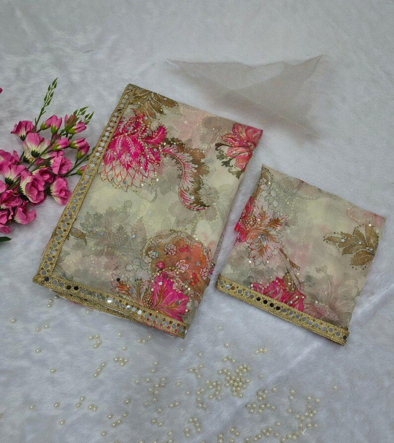 May include: A patterned fabric set with a large rectangular piece and a smaller square piece. The fabric has a cream background with pink, orange, and brown floral designs. The edges are trimmed with gold and small mirrors.