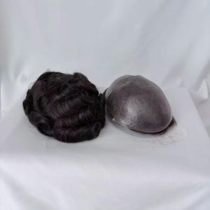 May include: Two dark brown hairpieces are displayed on a white surface. One hairpiece has tightly curled waves, while the other is a smooth, dome-shaped cap. The hairpieces appear to be for hair replacement or styling.