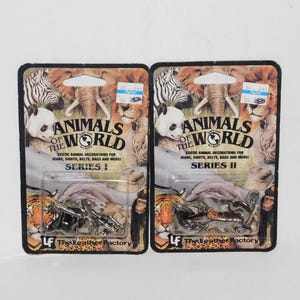 May include: Two packages of "Animals of the World" exotic animal decorations. Each package features a variety of animals, including a zebra, elephant, panda, lion, and tiger. The text "Series I" and "Series II" are visible.